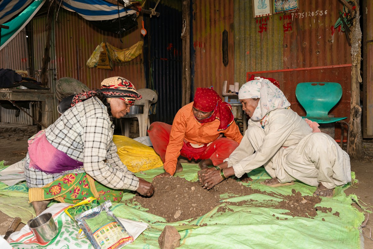 Women participating in a community service project, sitting around a pile of dirt, discussing family volunteer projects.