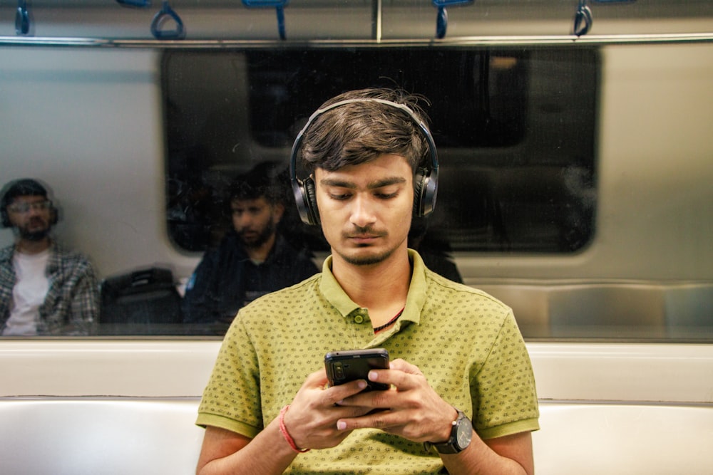 a man wearing headphones is looking at his cell phone