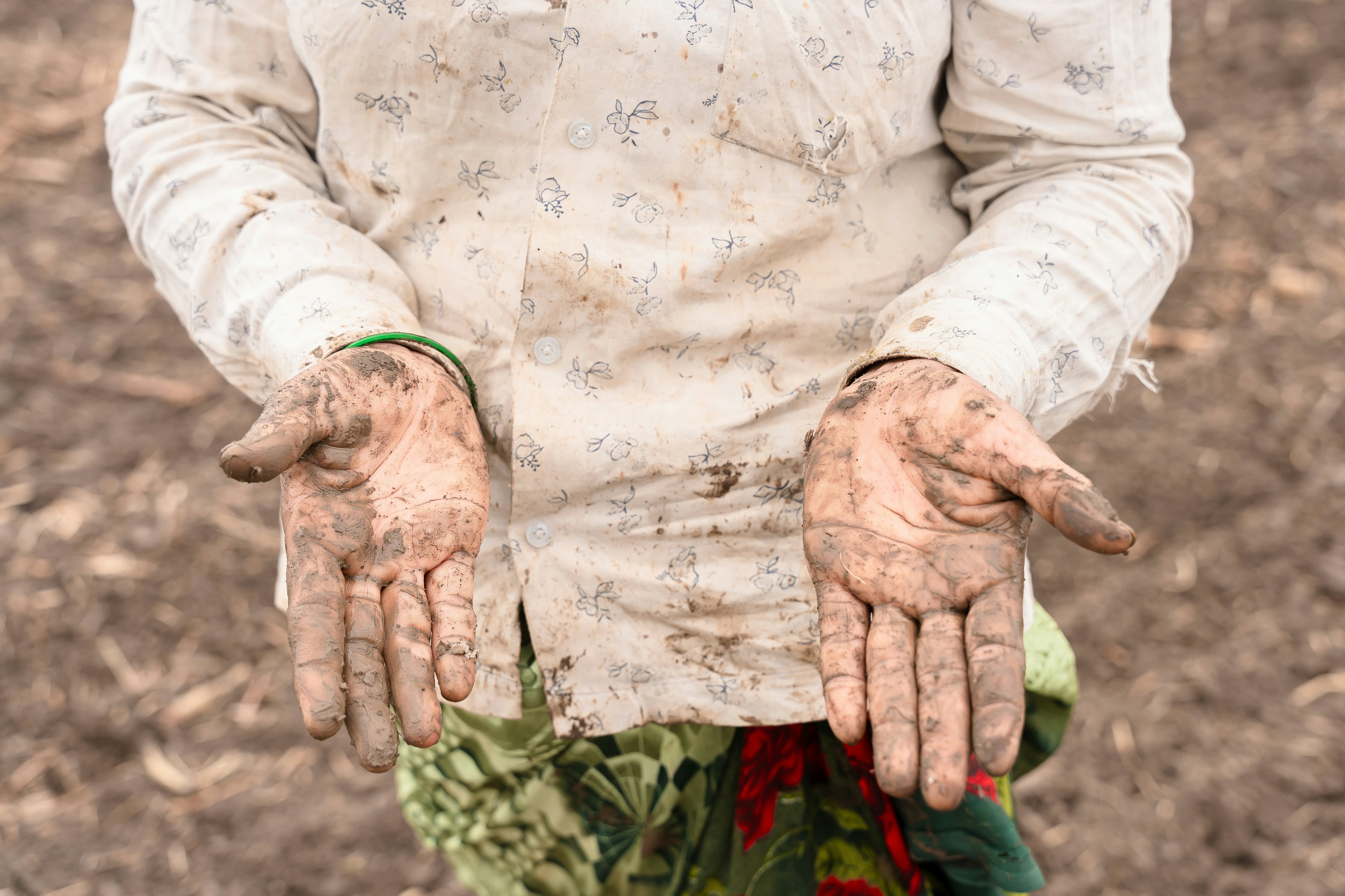 a person with dirty hands standing in a field