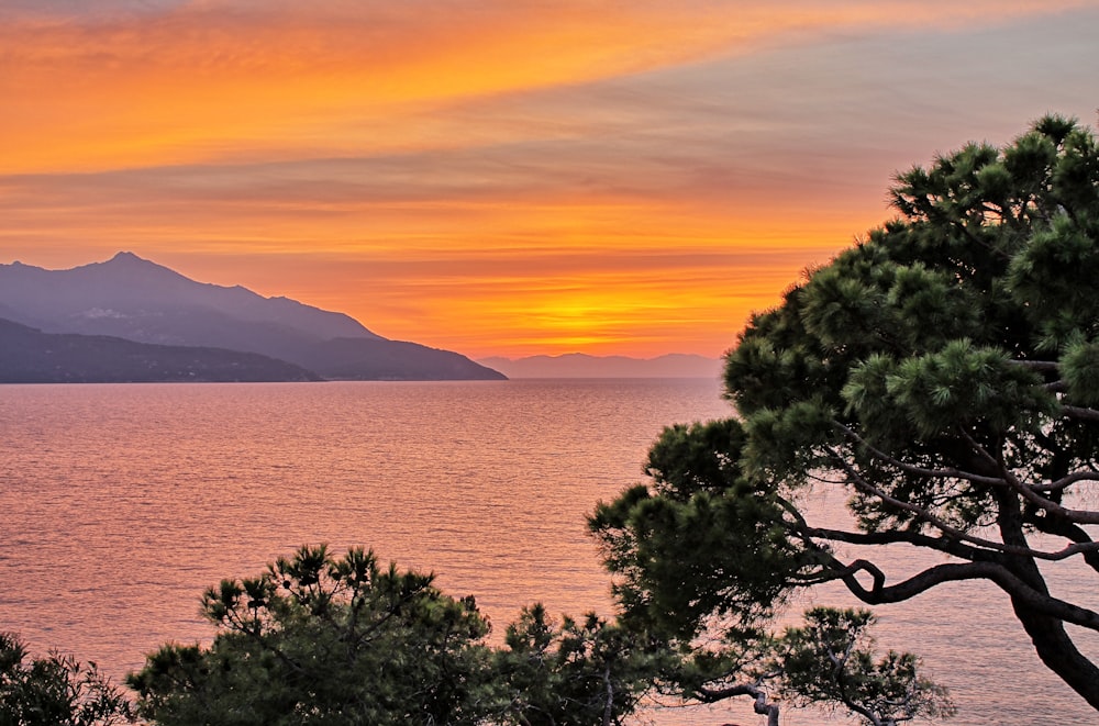 the sun is setting over the water and mountains