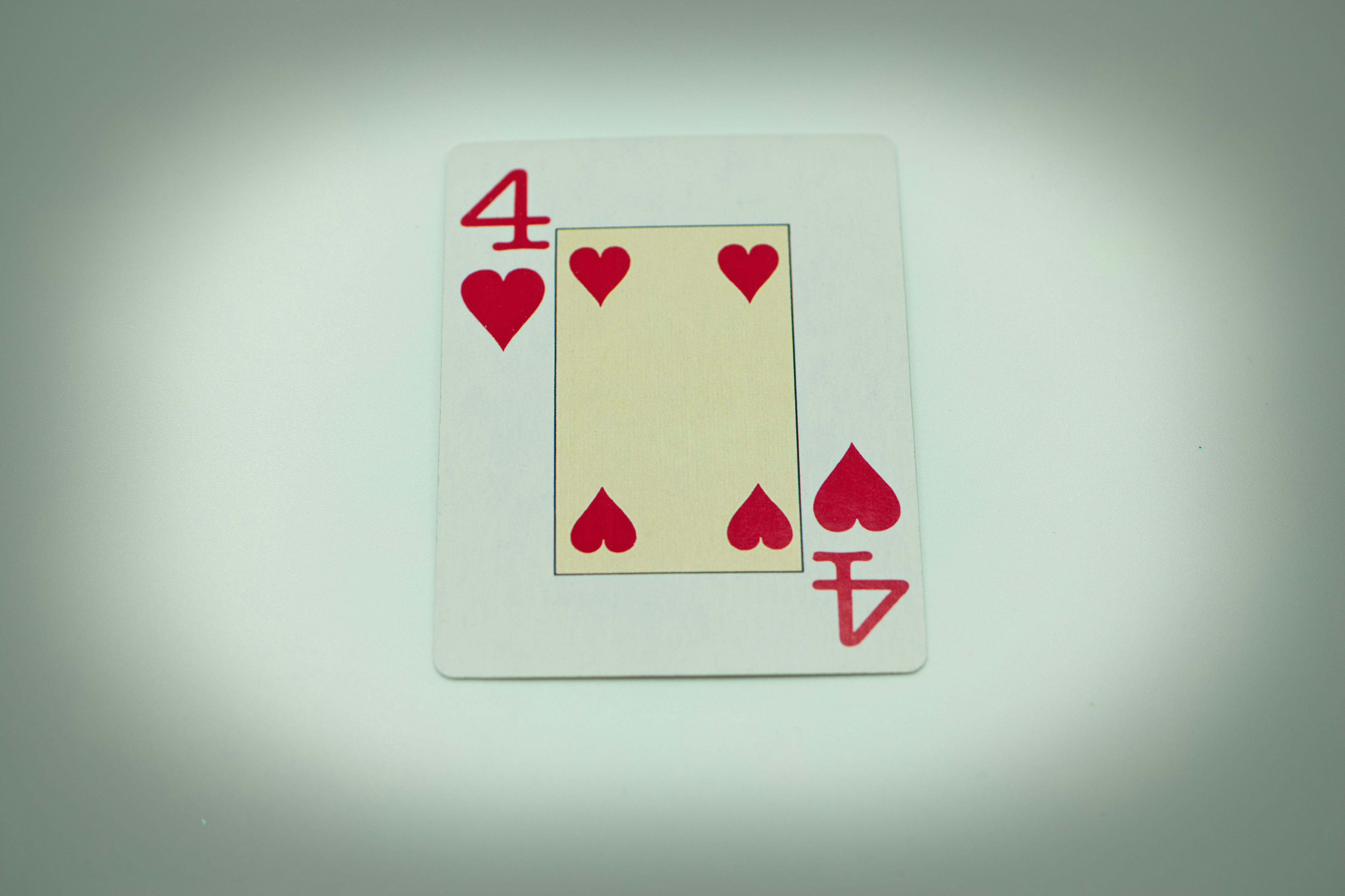 a four of hearts playing card on a table