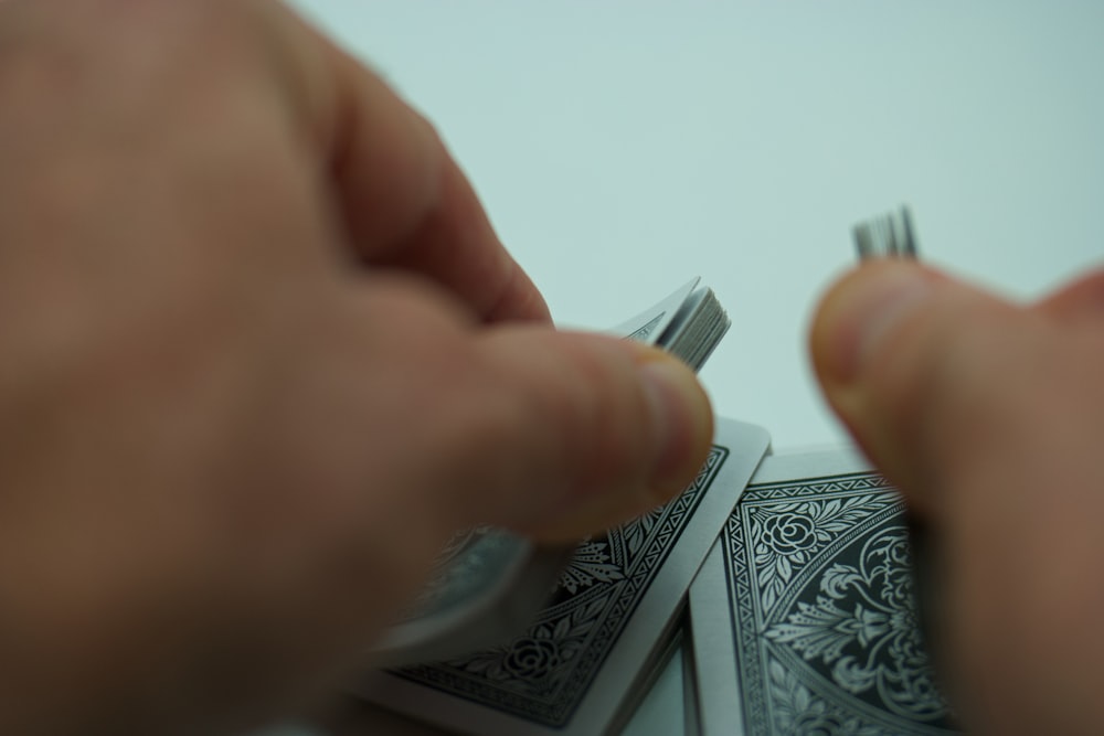 a person holding a toothbrush over a pile of playing cards