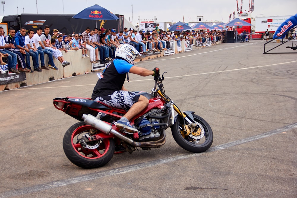 a man riding on the back of a red motorcycle