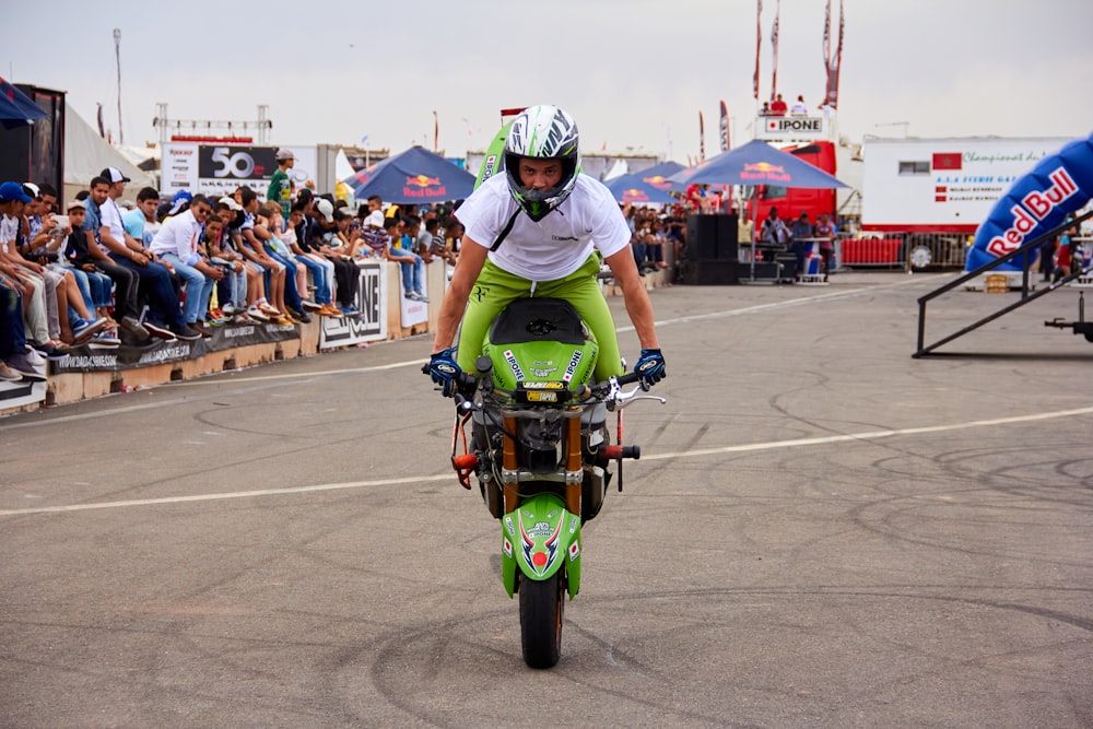 a man riding a green motorcycle on top of a race track