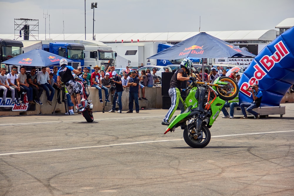 a man riding a green motorcycle down a street