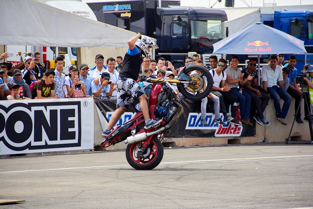 a person on a motorcycle doing a trick in front of a crowd