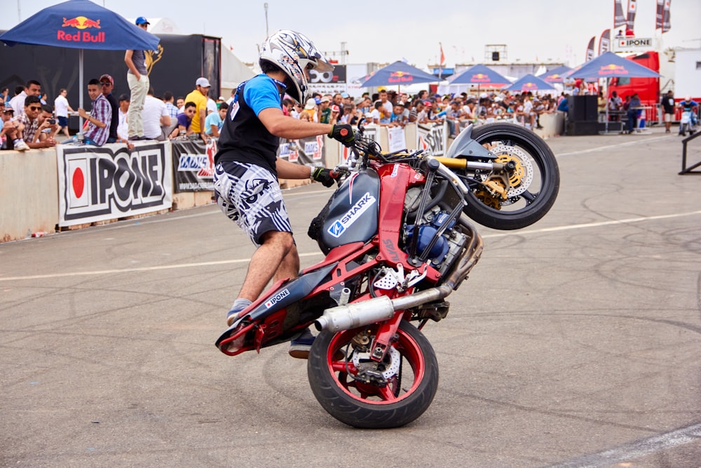 a man doing a wheelie on a red motorcycle