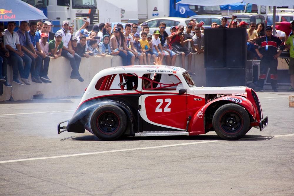 a red and white car driving down a race track