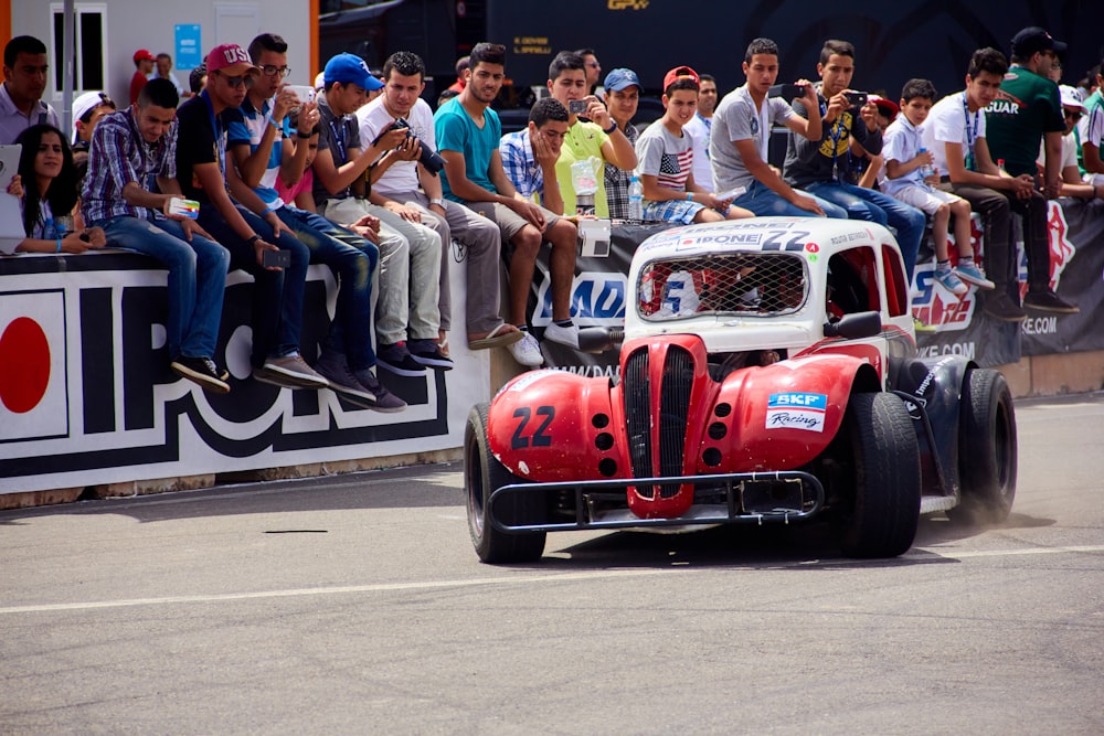 a red and white race car driving past a crowd of people