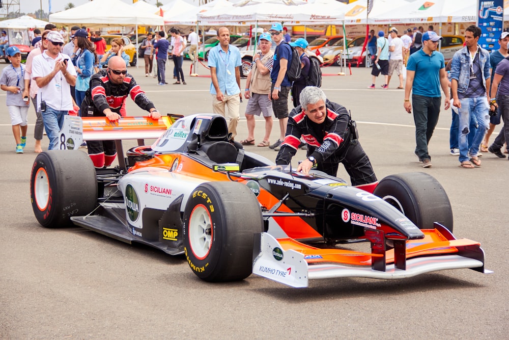 a man in an orange and white race car on a race track