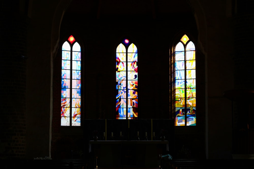 two stained glass windows in a church with pews