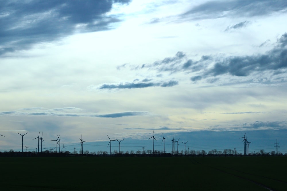 a group of windmills in a field under a cloudy sky