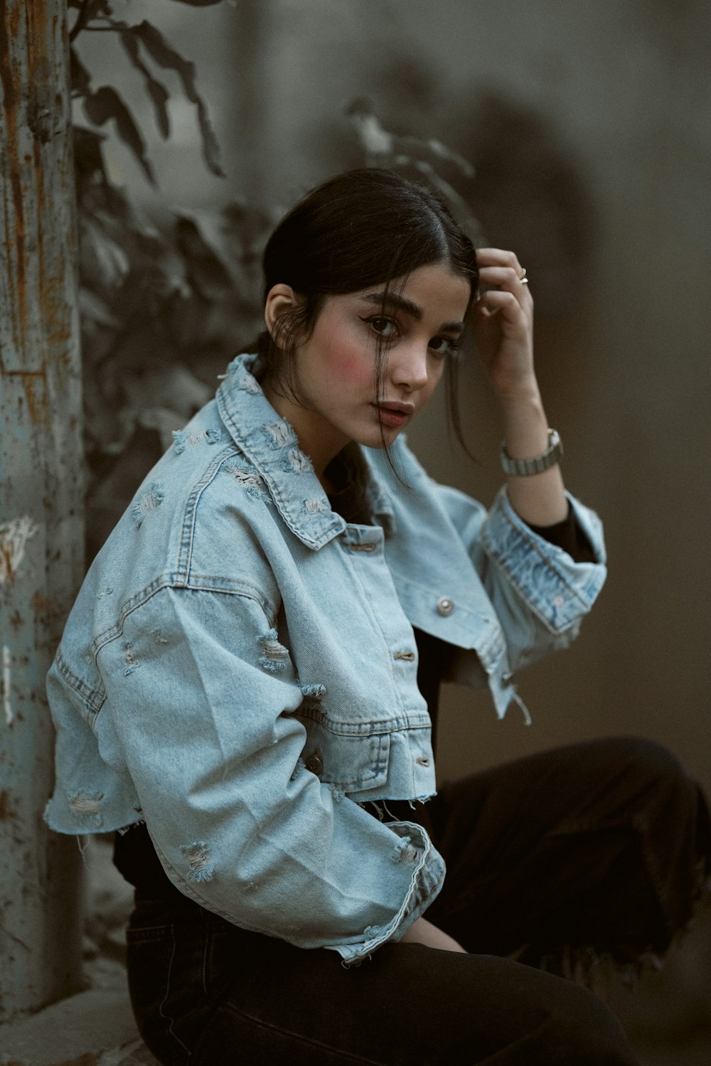 a woman sitting on the ground wearing a jean jacket