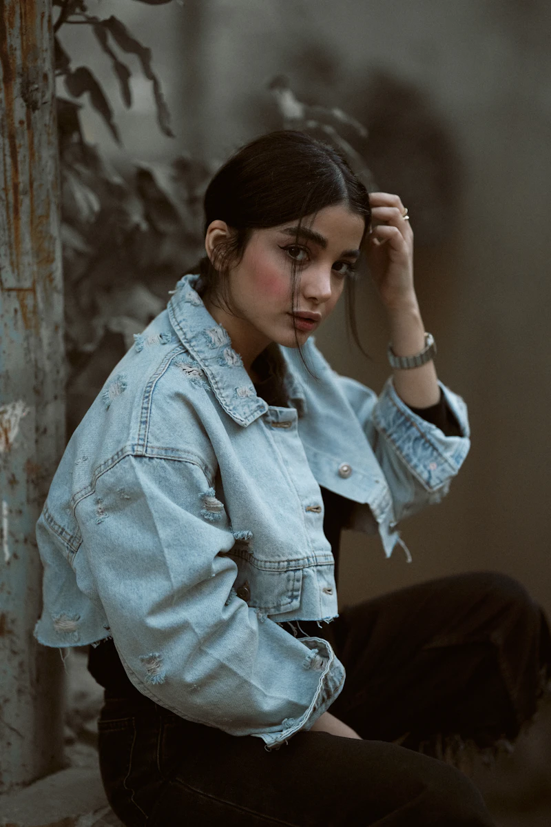 woman wearing a denim jacket sitting outdoors