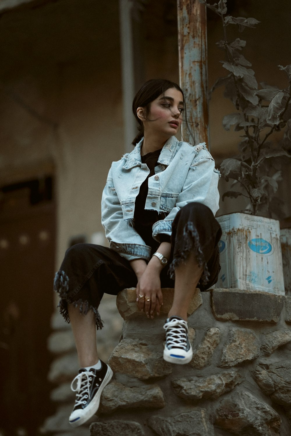 a woman sitting on top of a stone wall