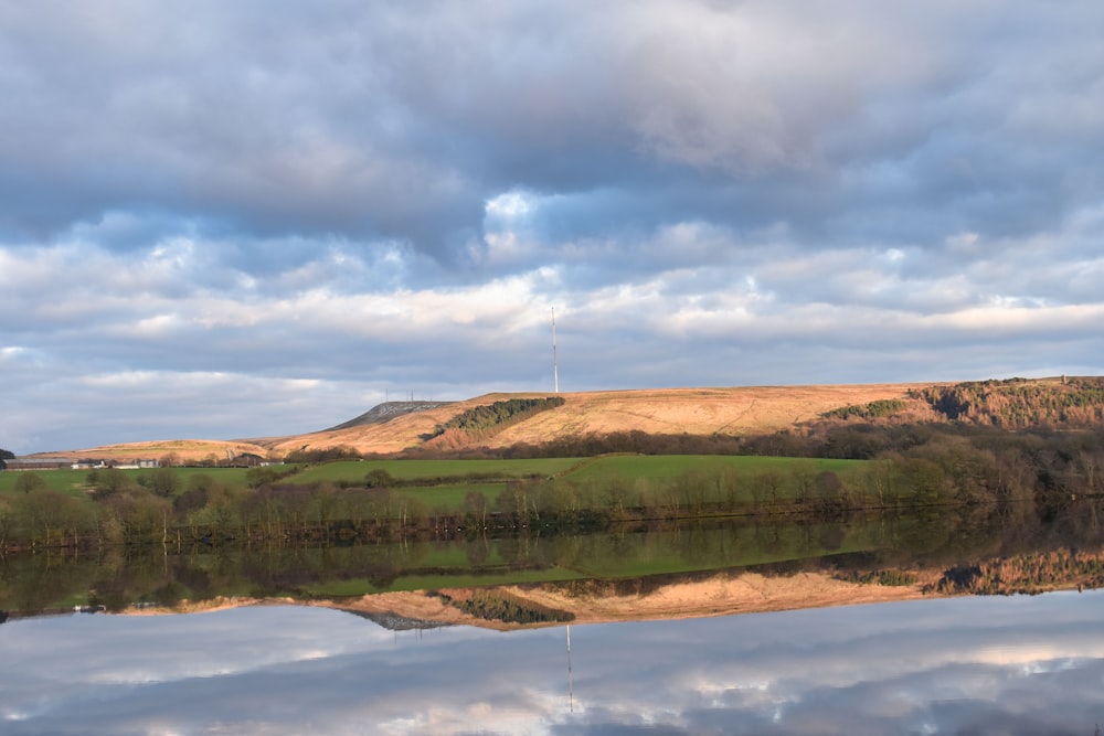 a large body of water surrounded by a lush green hillside