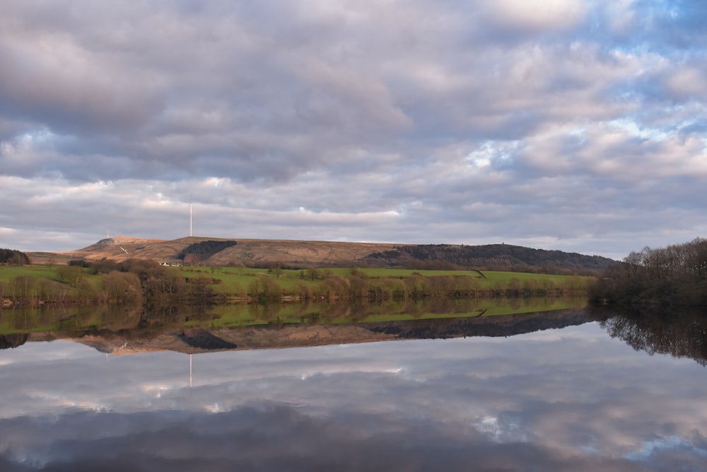 a large body of water surrounded by a lush green hillside