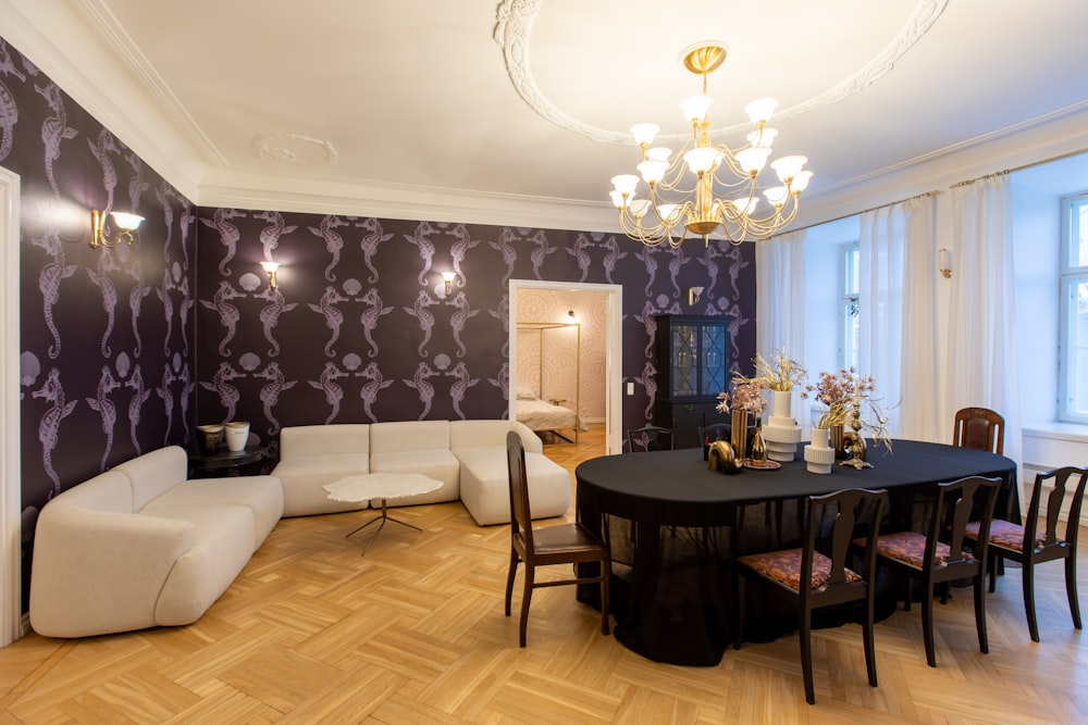 a room with a table, chairs, couches and a chandelier