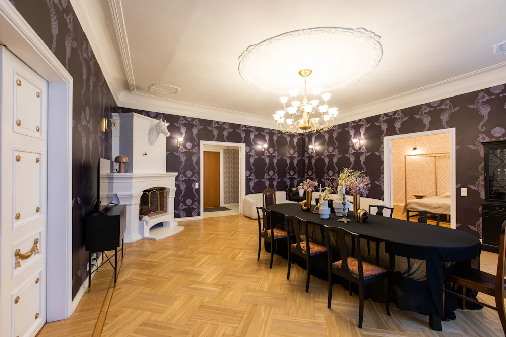 Sala de jantar com papel de parede escuro padronizado e mesa comprida