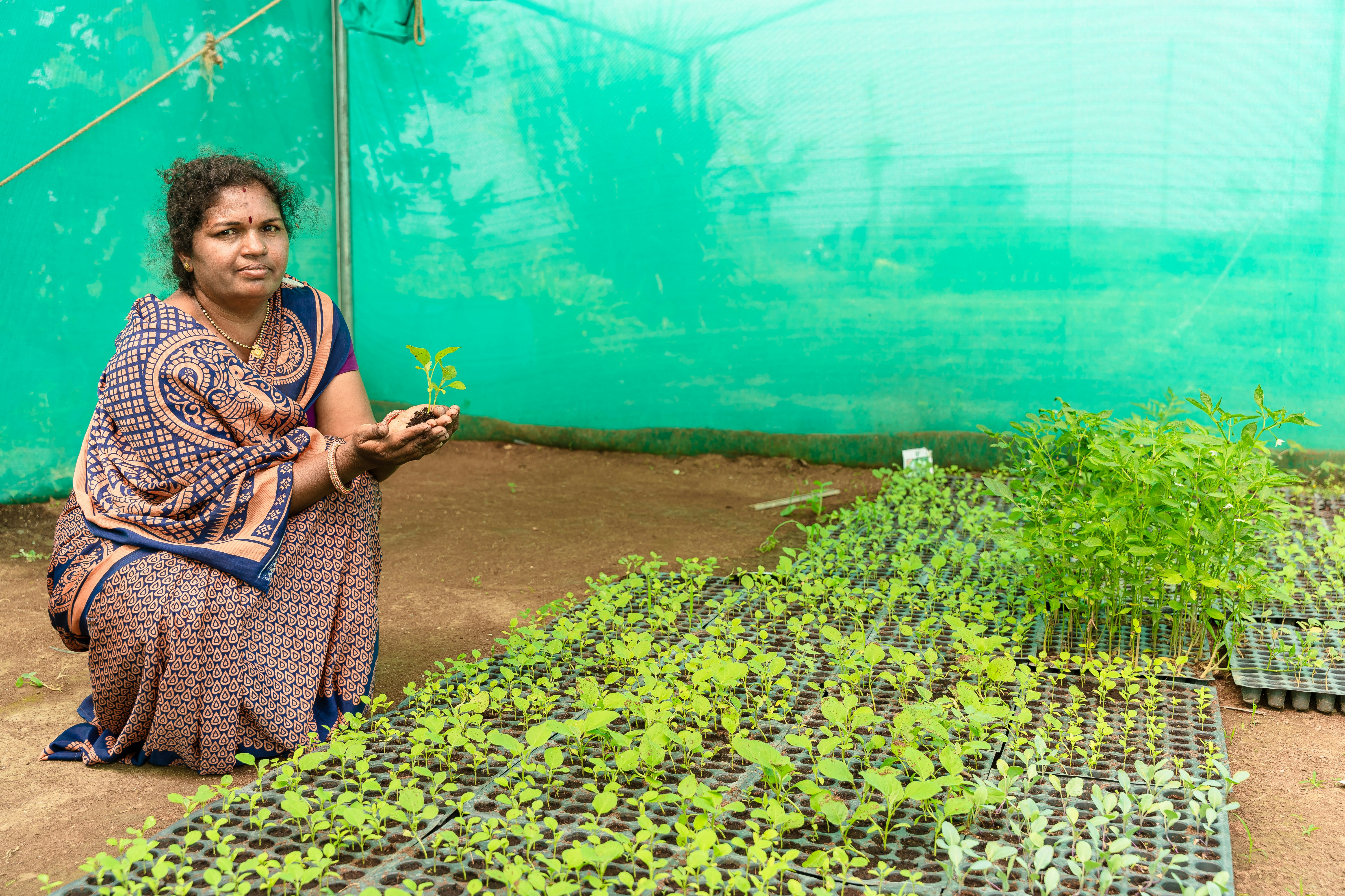 a woman kneeling down in front of a bunch of plants