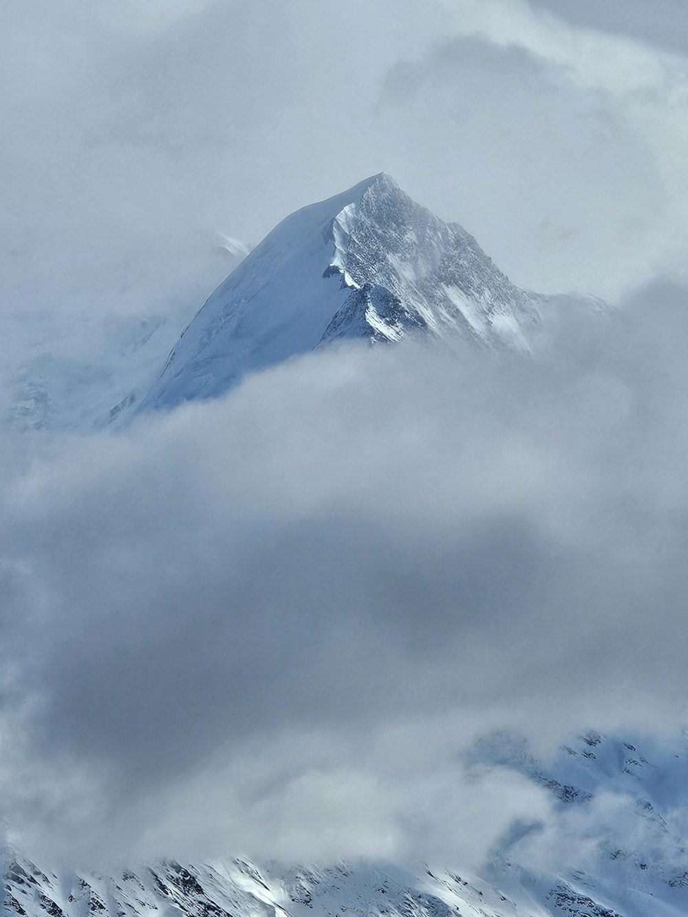 a snow covered mountain in the middle of a cloudy sky