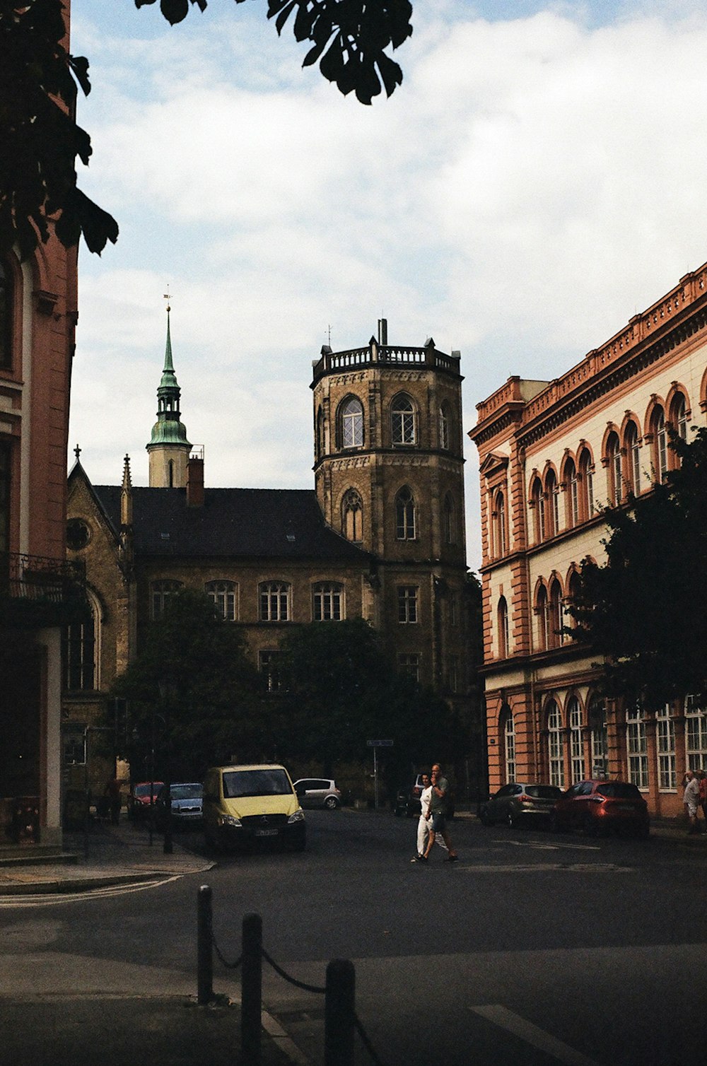 a couple of people walking down a street next to tall buildings