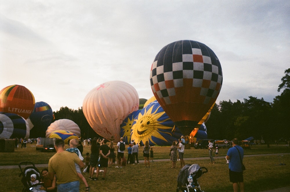 a group of people standing around a bunch of hot air balloons