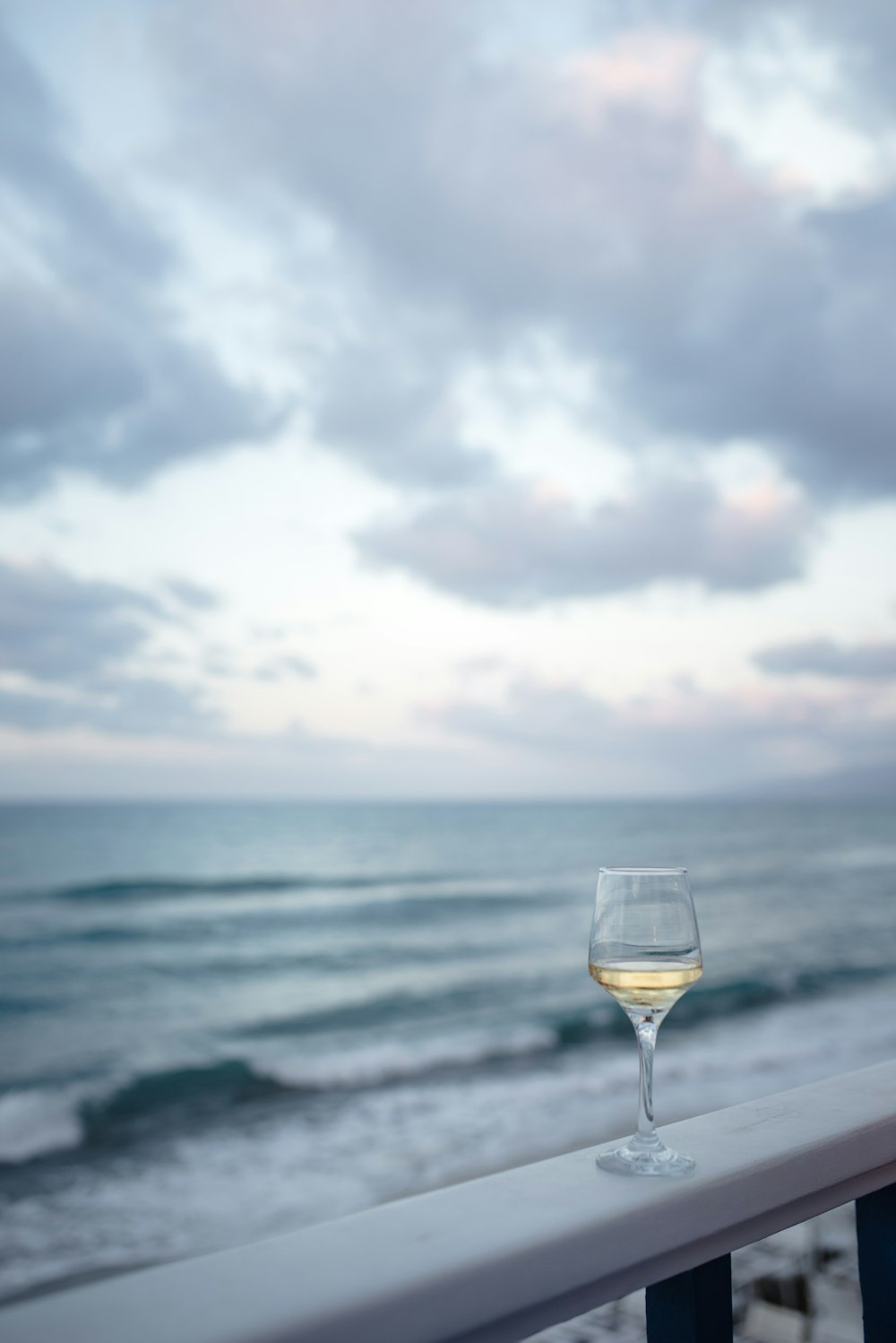 a glass of wine on a balcony overlooking the ocean