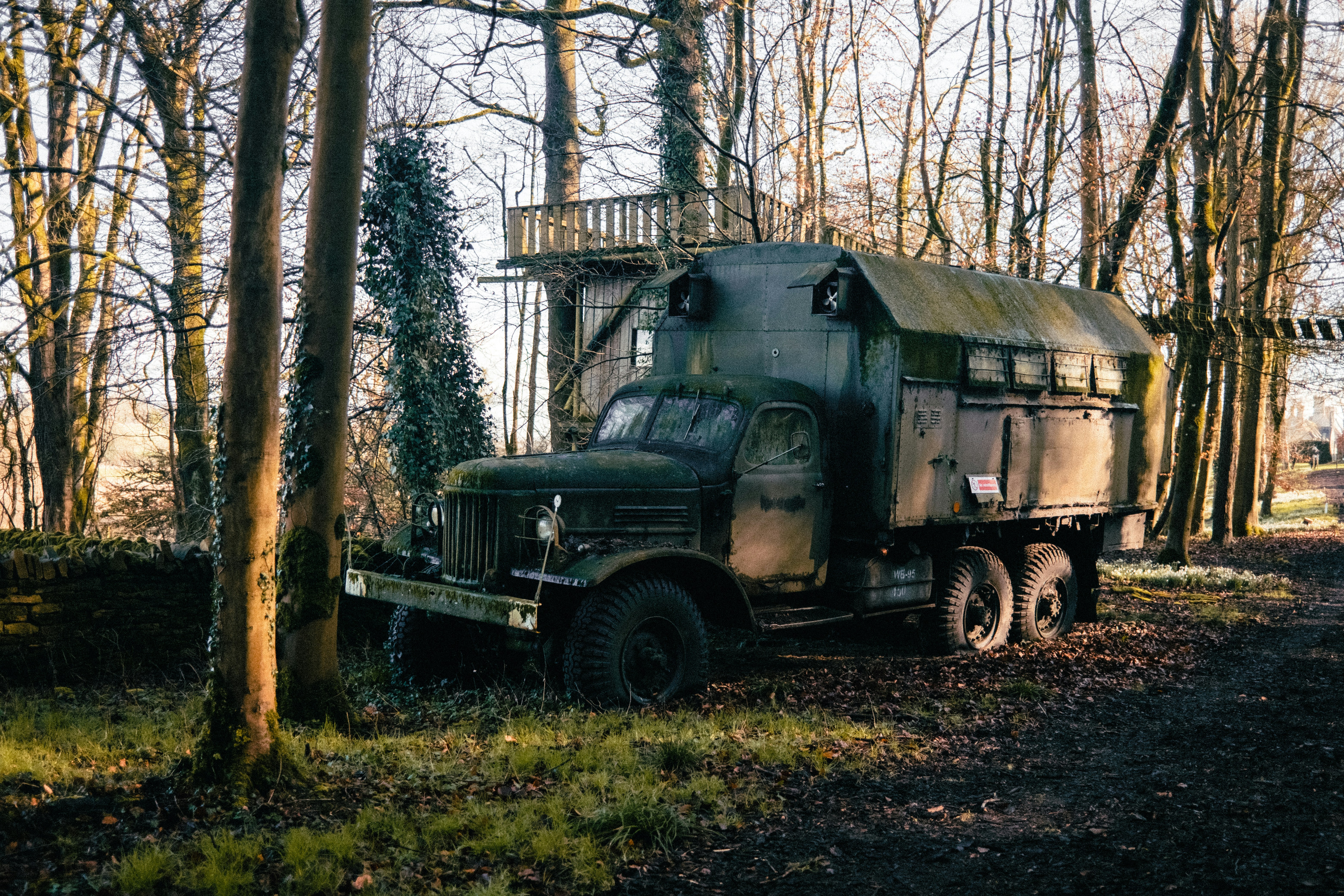 an old military truck parked in a wooded area