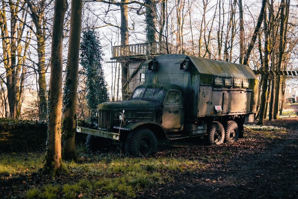 an old military truck parked in a wooded area