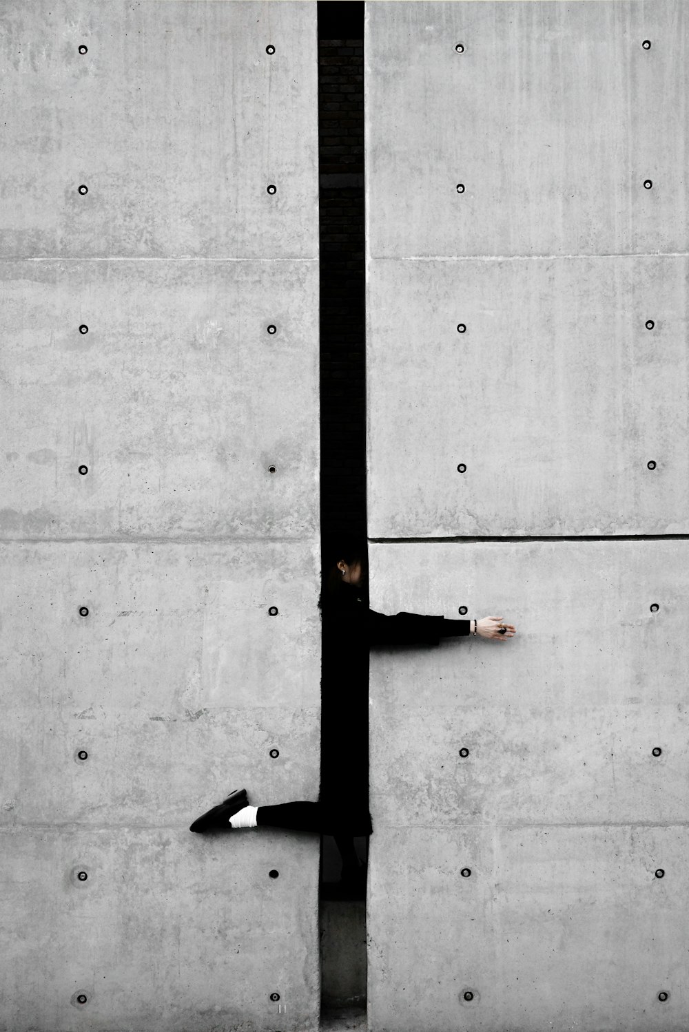 un uomo appoggiato a un muro con la mano su un palo
