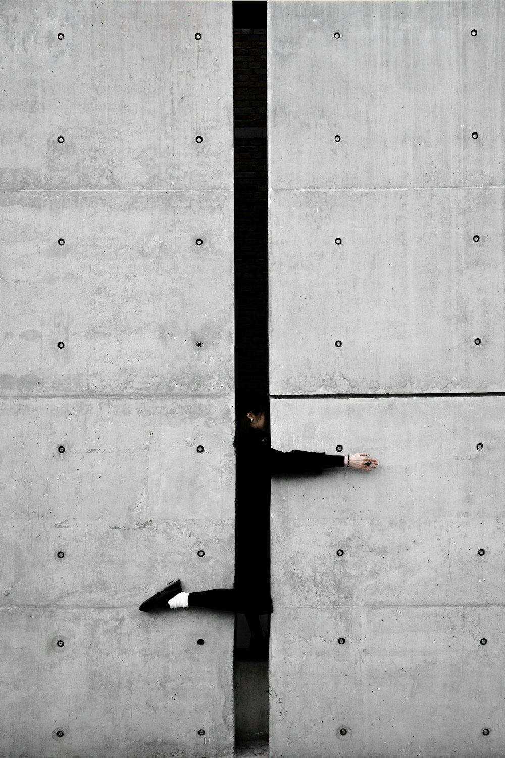 a man leaning against a wall with his hand on a pole