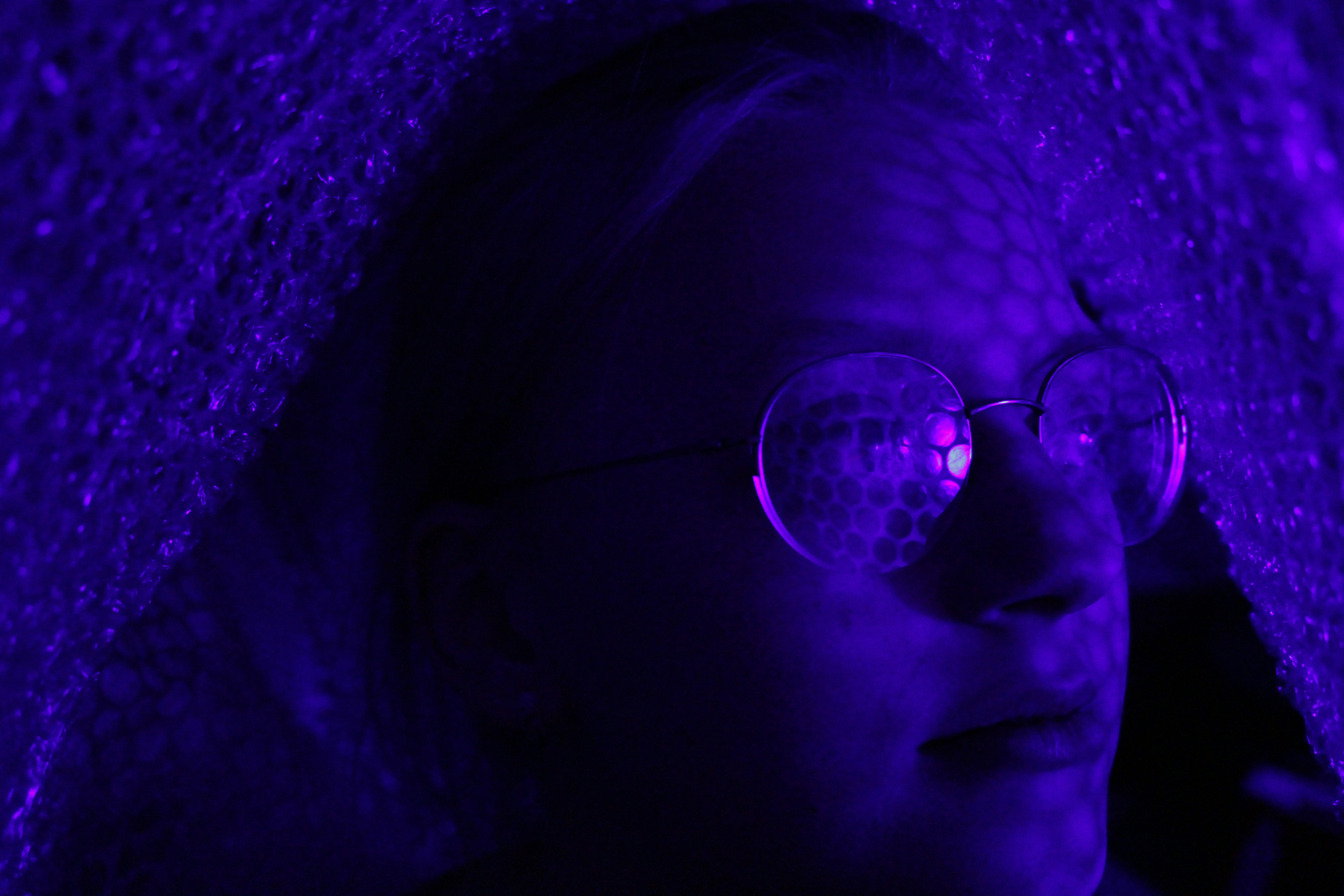 a woman wearing glasses and a purple light