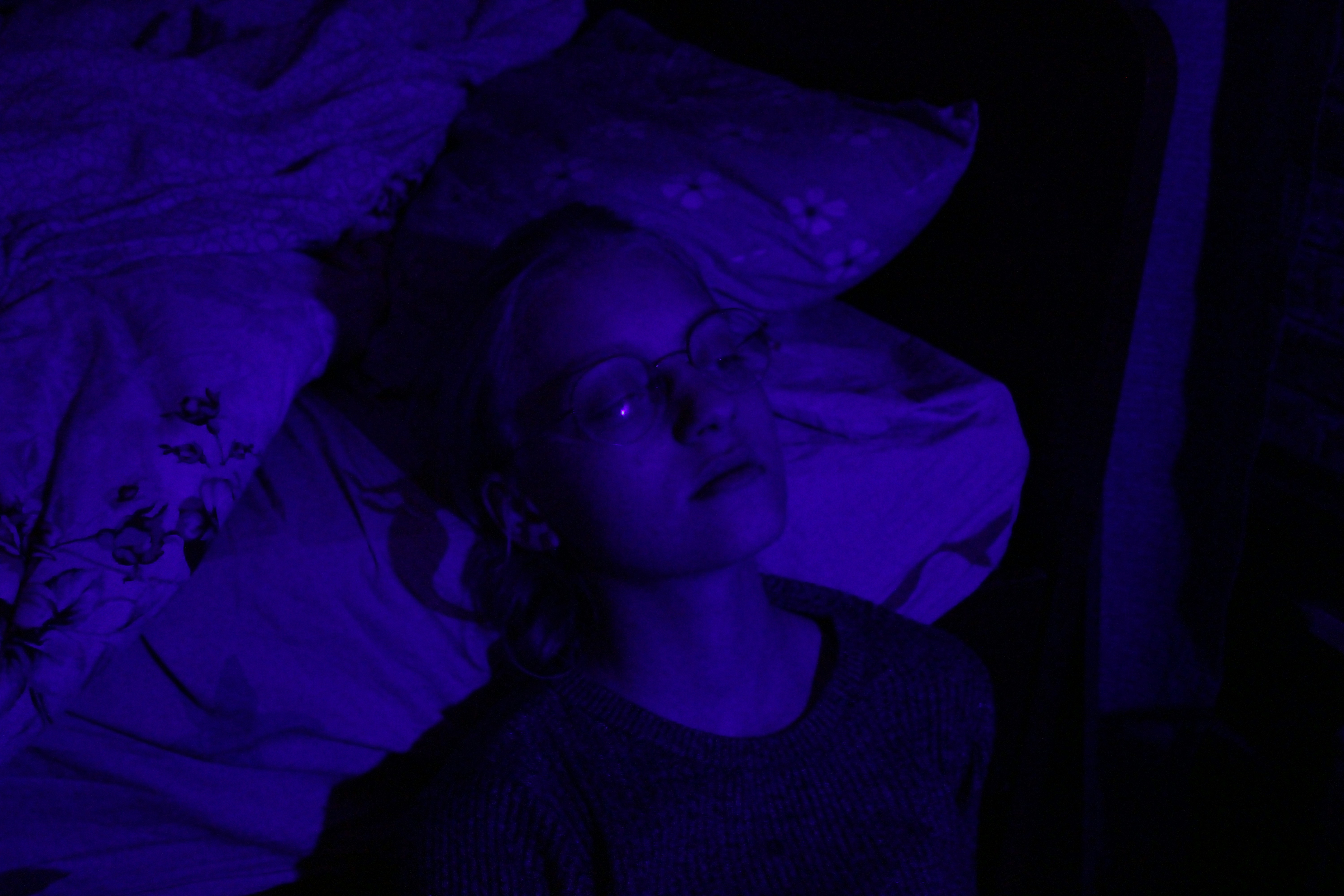 a woman laying in a bed with purple light