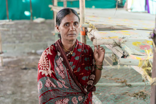 A woman in a red sari standing outdoors in a rural setting