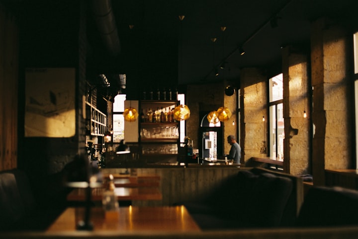 Dimly lit dining room with tables and chairs, photo by Oliver Guhr on Unsplash
