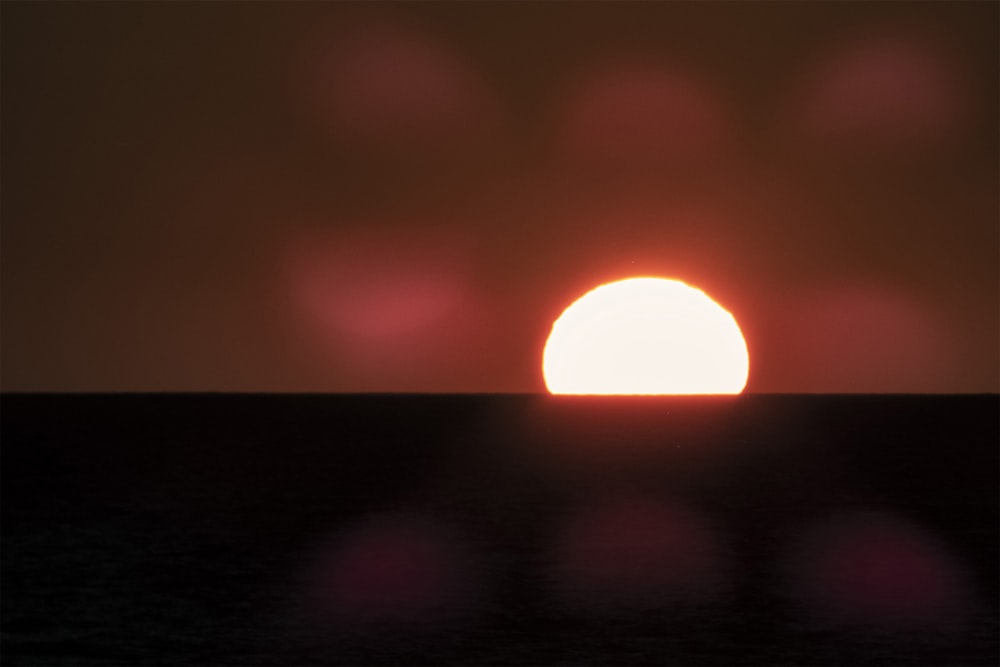 the sun is setting on the horizon of a body of water