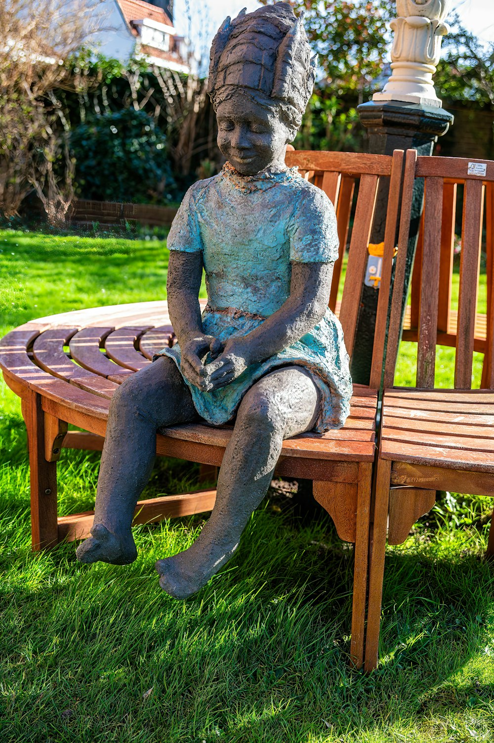 a statue of a girl sitting on a wooden bench