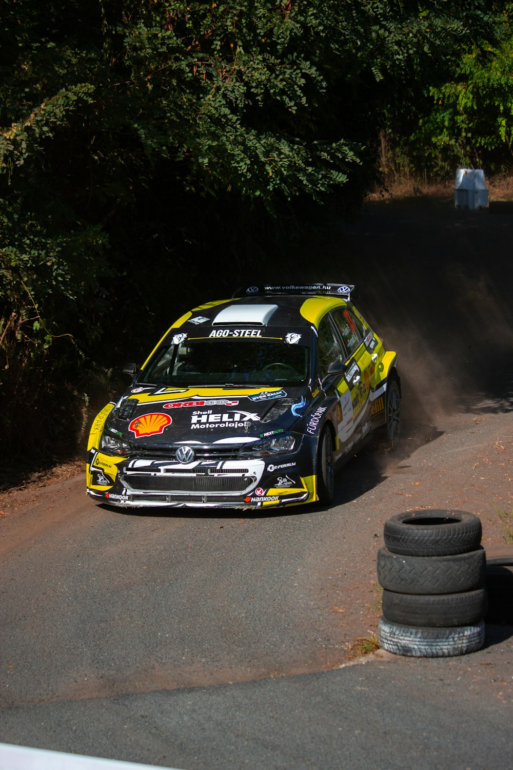 a yellow and black car driving down a dirt road