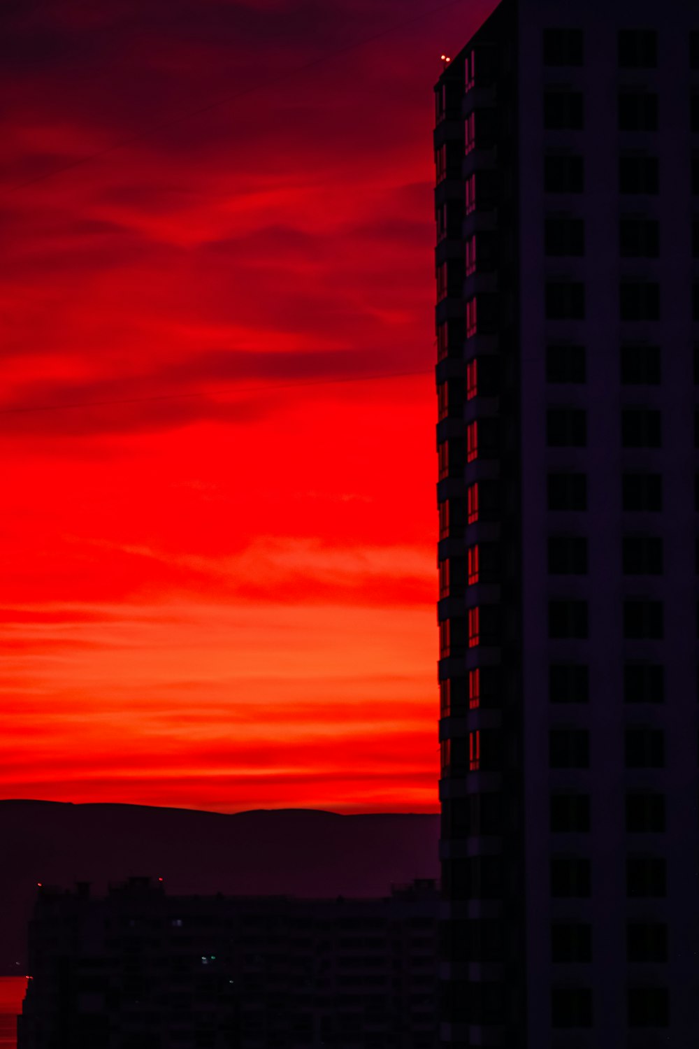 a very tall building with a red sky in the background