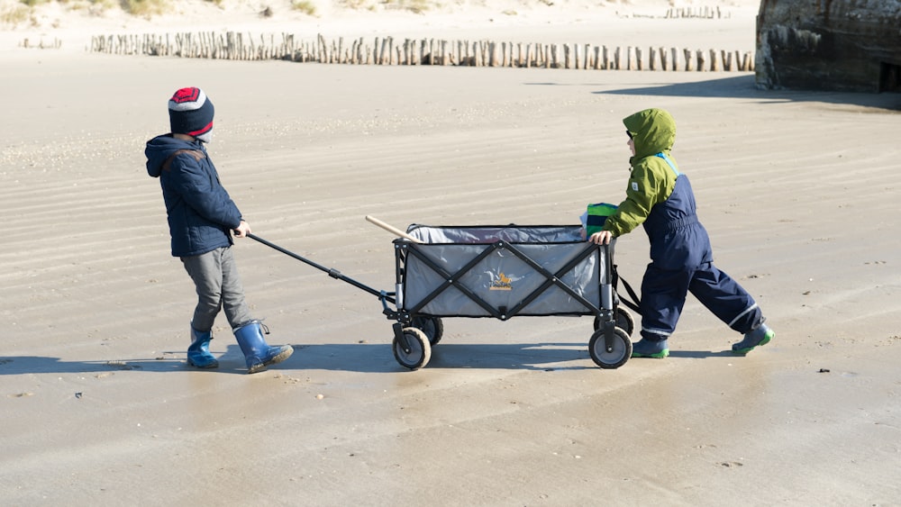 two children pushing a wagon on the beach