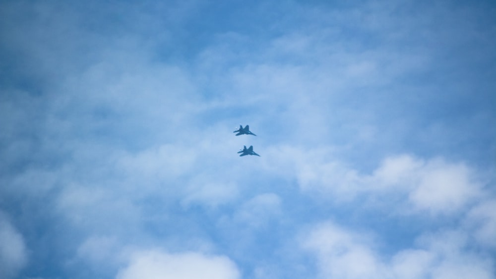 two airplanes flying in the sky on a cloudy day