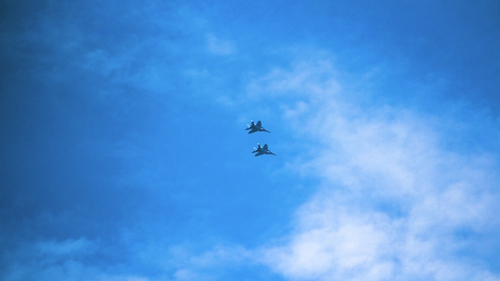 two planes flying in the sky on a cloudy day
