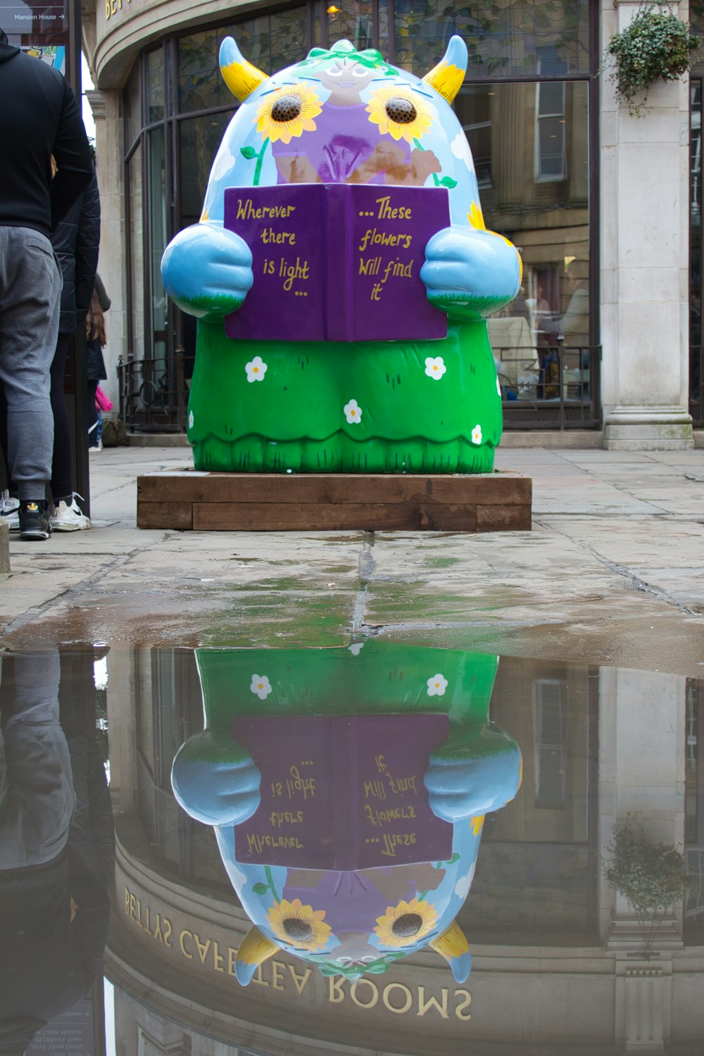 a statue of a cow with a book in its mouth