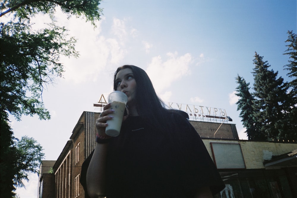 a woman in a black dress holding a cup of coffee