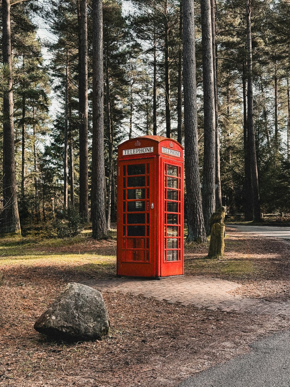 a red phone booth sitting in the middle of a forest