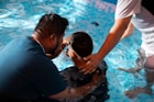 a group of people standing around a swimming pool