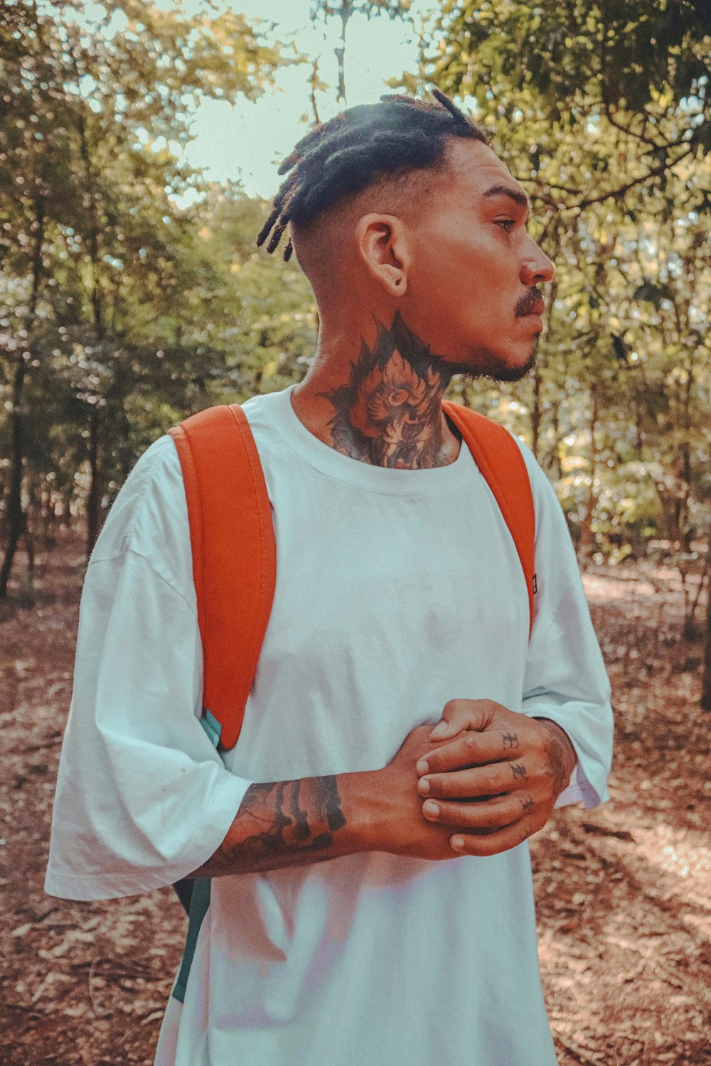a man with dreadlocks and a backpack in the woods