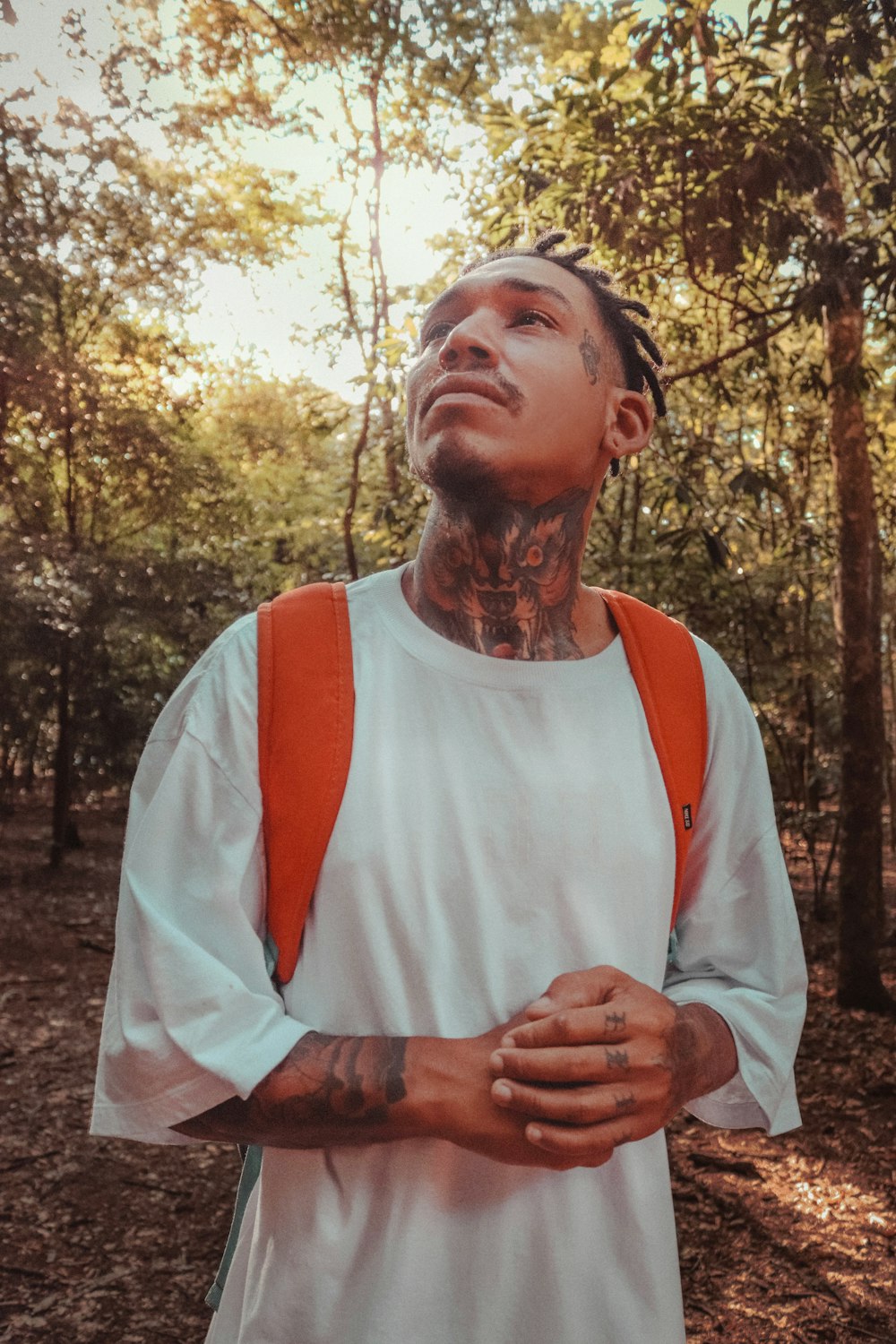 a man with tattoos standing in the woods