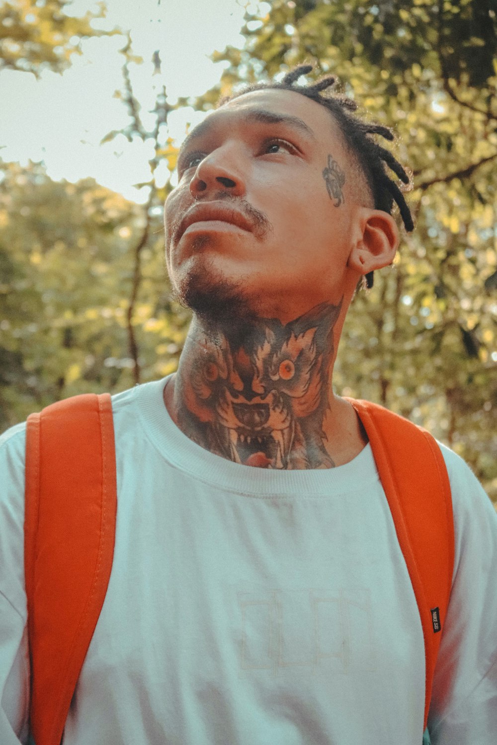 a man with tattoos and a backpack looking up